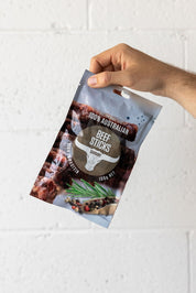 Hand holding up a pouch of beef sticks