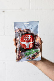 hand holding chilli beef biltong up in the air