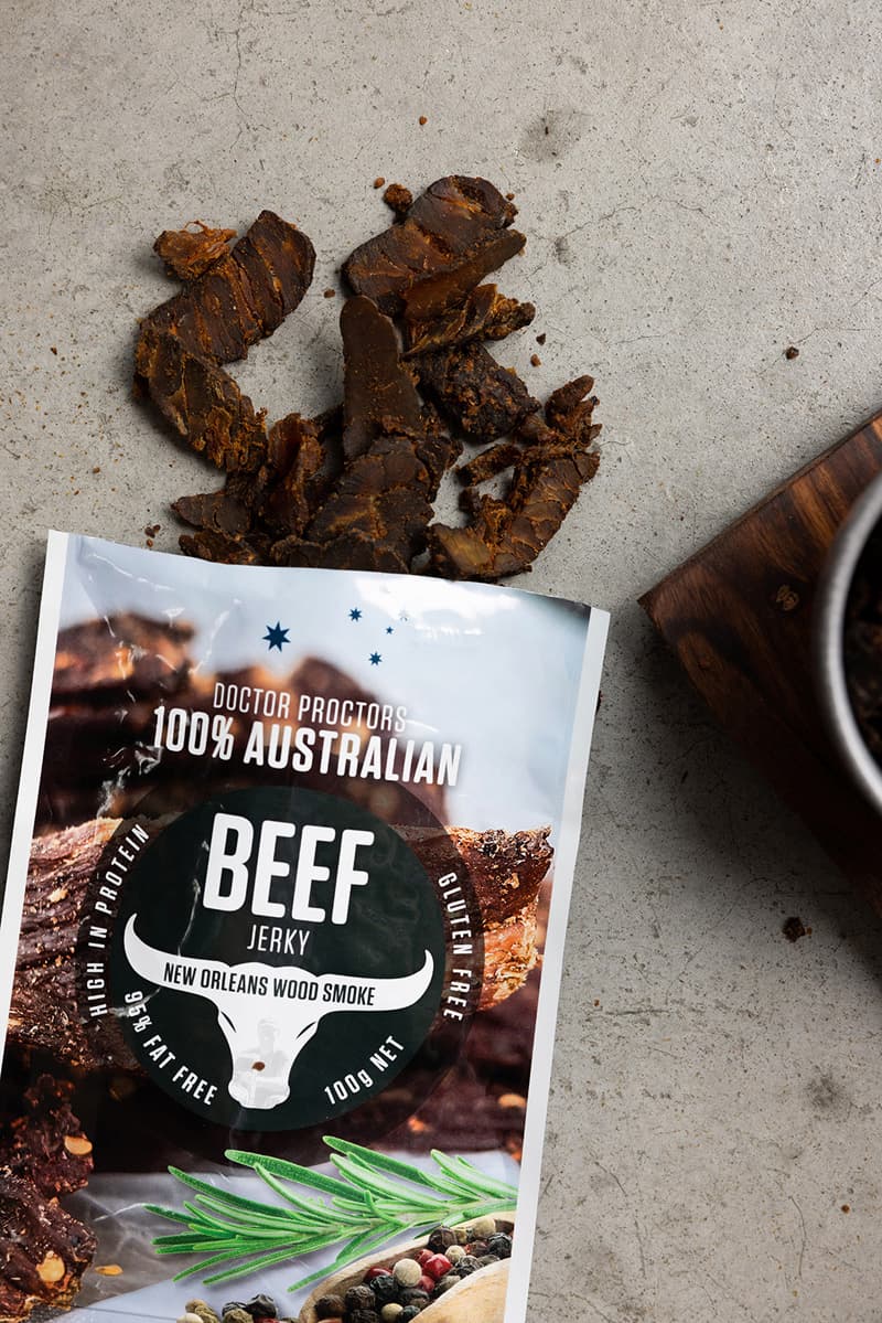 Wood smoked beef jerky on ground with smoked jerky next to it