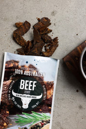 Wood smoked beef jerky on ground with smoked jerky next to it