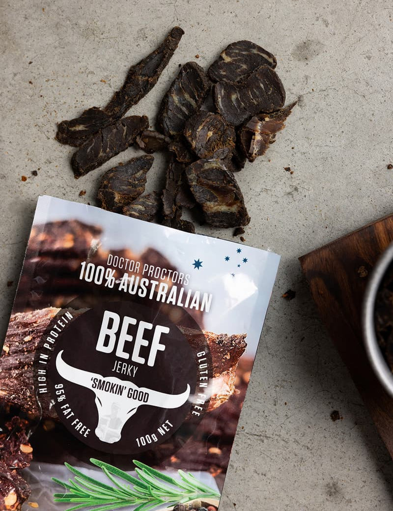 Pouch of smoked beef jerky on table next to fatty and tended pieces of jerky