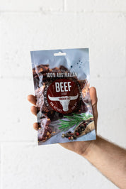 Hand holding pouch of beef jerky in the air