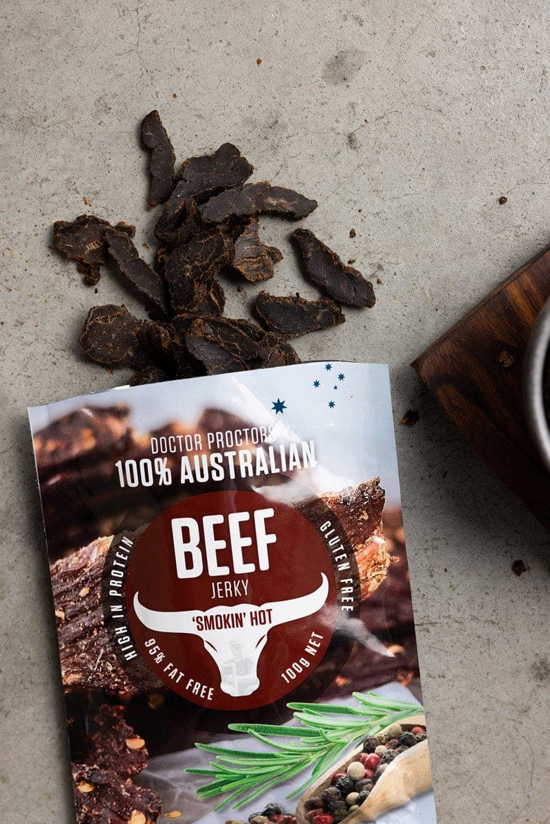Beef jerky pouch on ground flatlay with pieces of loose jerky next to it