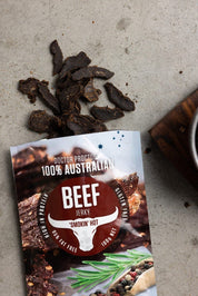 Beef jerky pouch on ground flatlay with pieces of loose jerky next to it