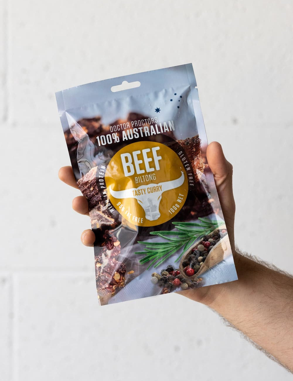 Hand holding large pouch of curry biltong in the air