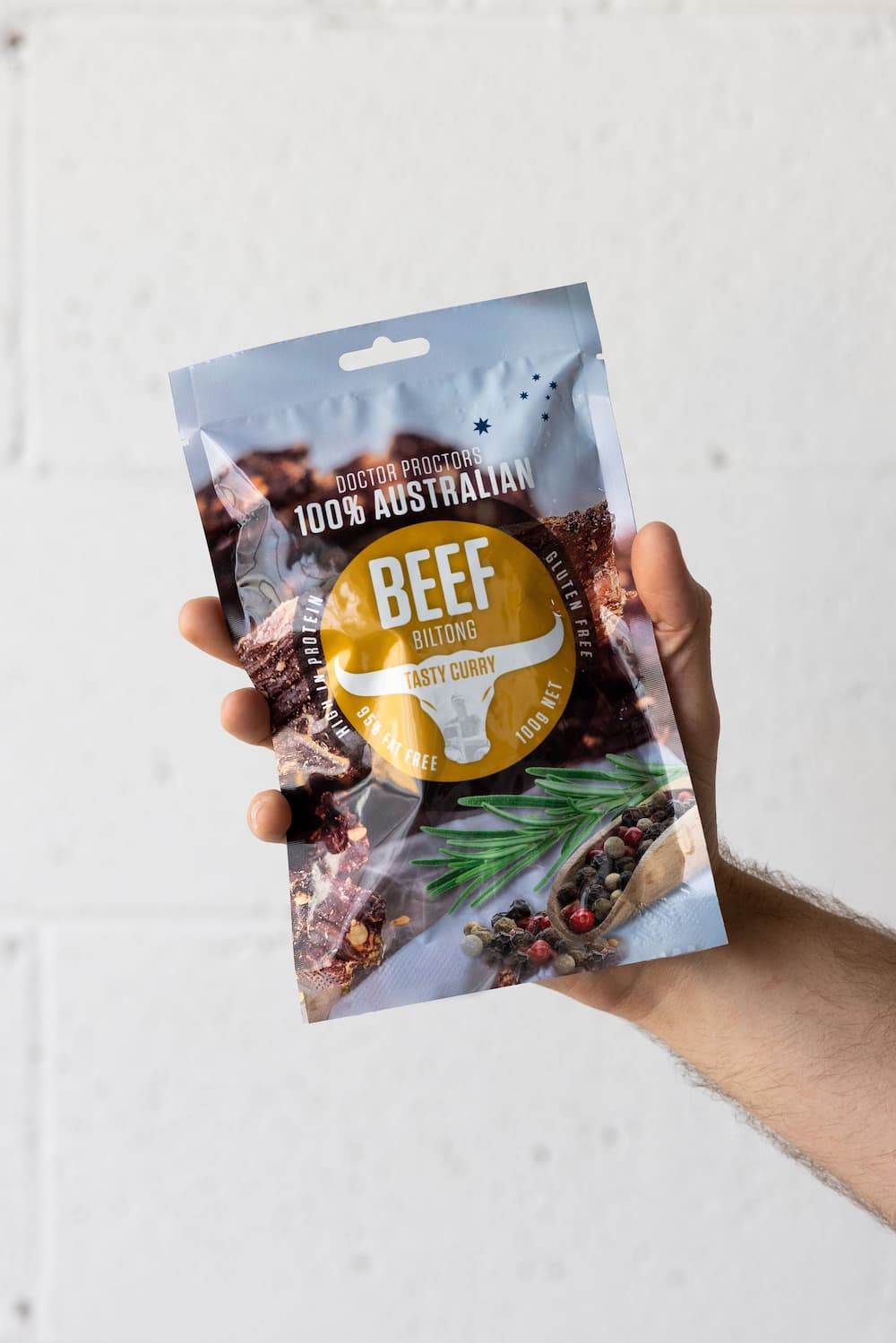 Hand holding large pouch of curry biltong in the air
