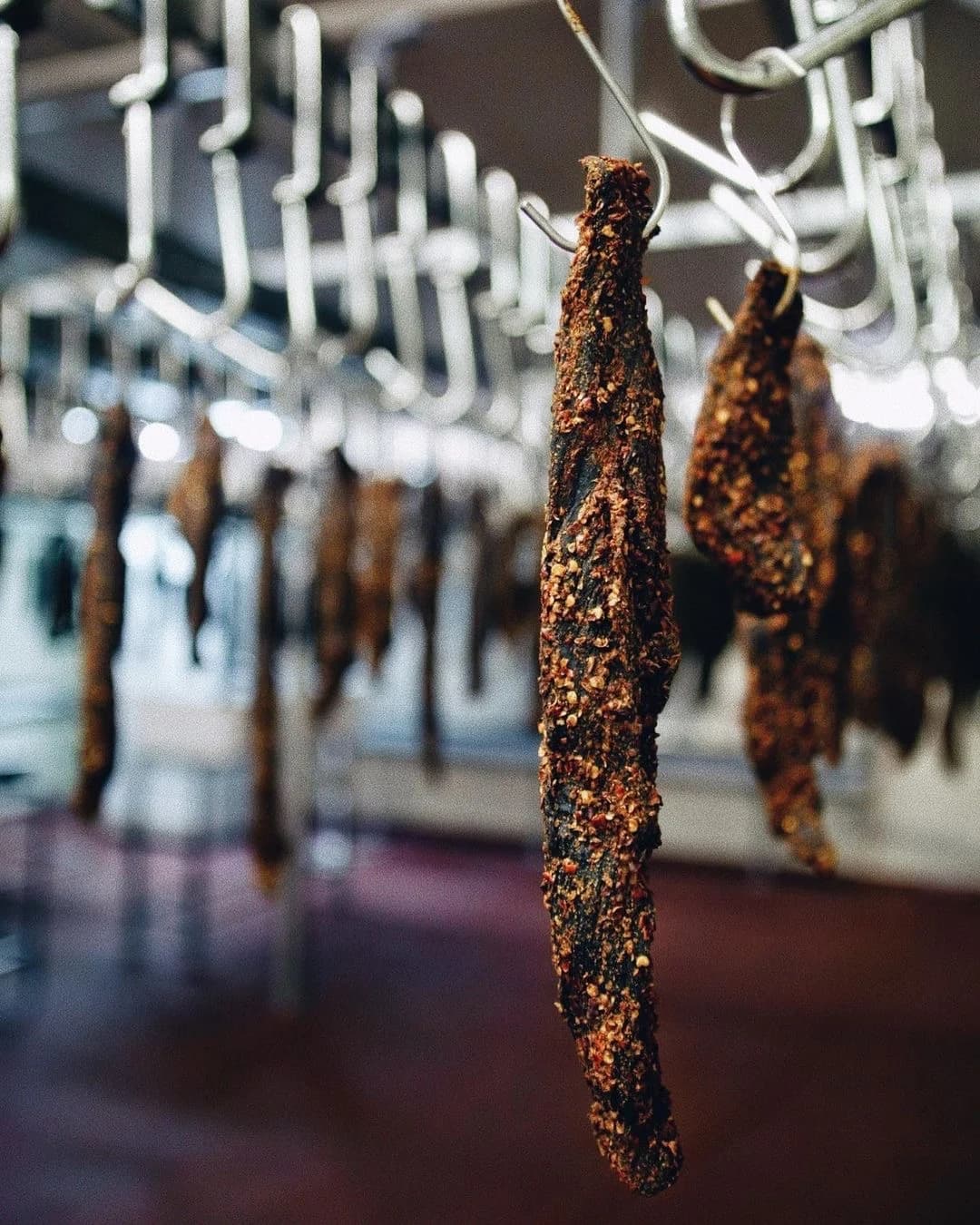 Whole pieces of beef biltong hanging up in the drying room