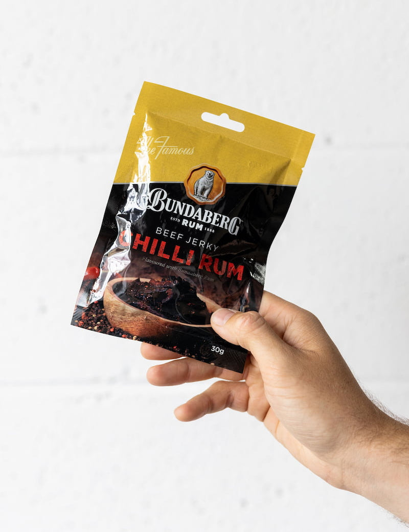 Hand holding beef jerky pack up in the air