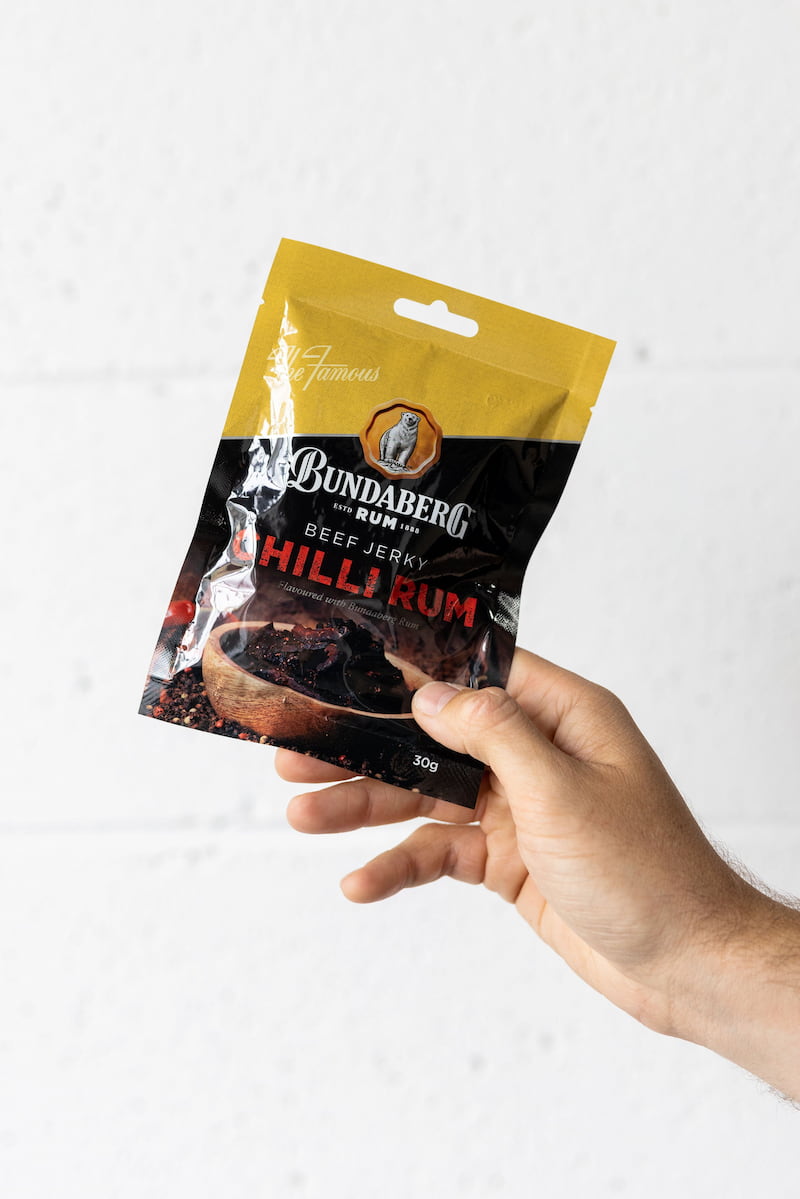 Hand holding beef jerky pack up in the air
